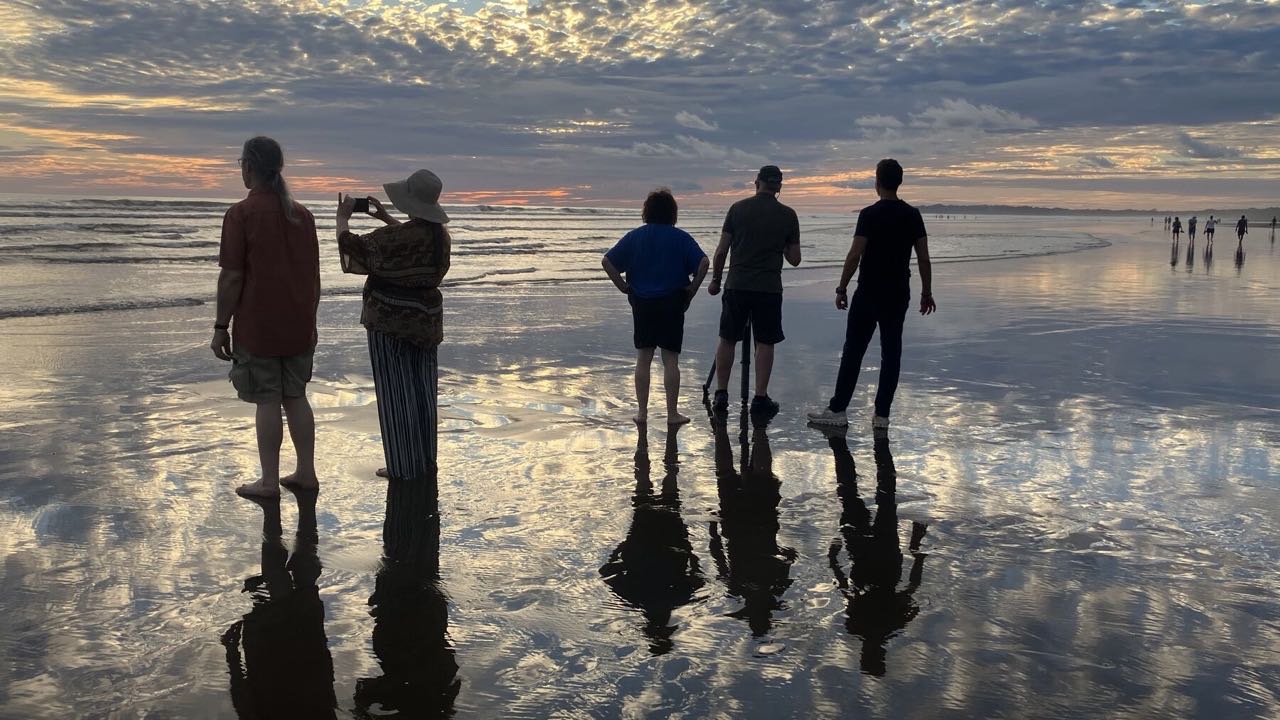 Mars Can Wait trailer: five people on a wet beach at sunset, looking out to sea